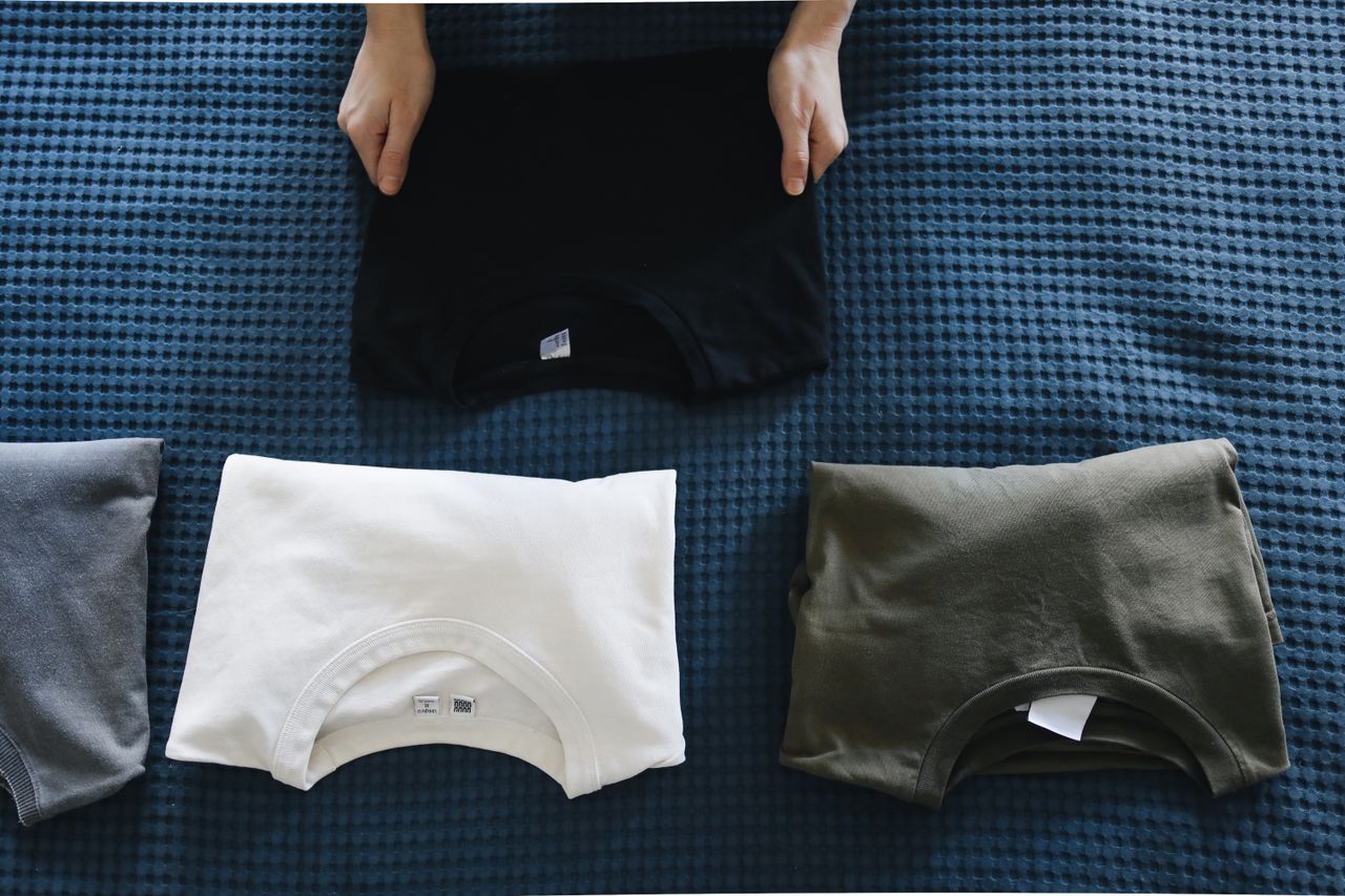 Top view of neatly folded colored T-shirts laid out on a blue bedspread, perfect for housekeeping themes.
