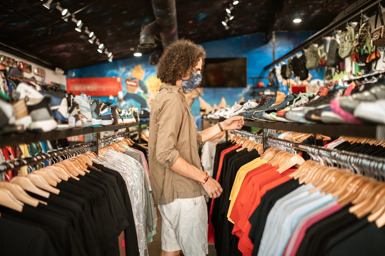 journey A fashionable young man shops for clothes in a trendy urban store, wearing a mask.